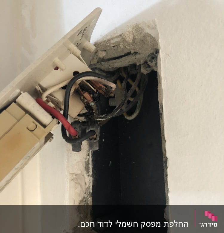 חוטי חשמל חשופים בקופסת חיבורים בקיר